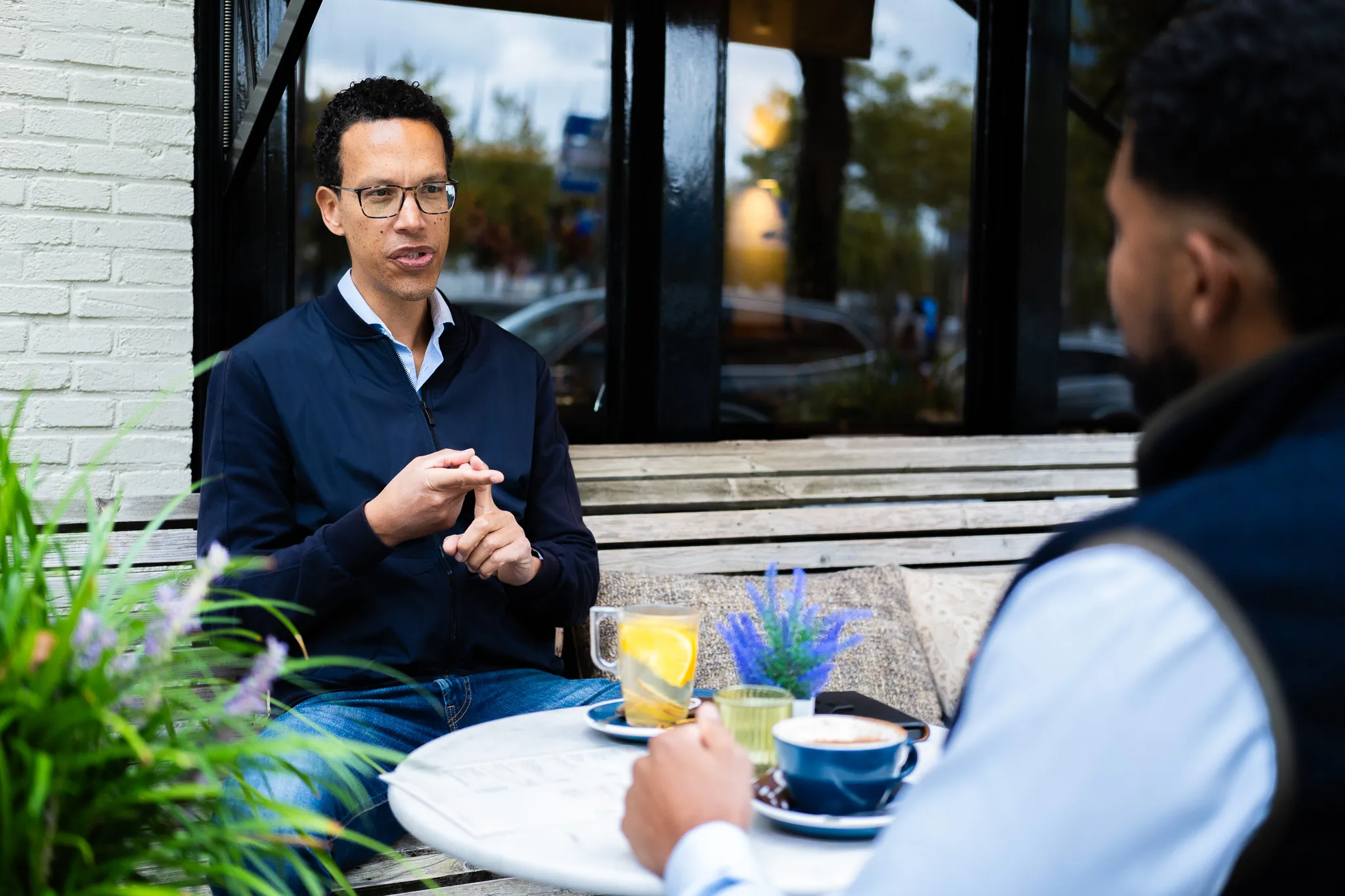 Twee personen in gesprek aan een tafeltje buiten bij een café